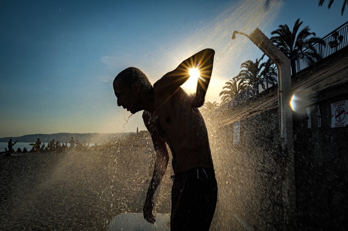 A man takes a shower on the beach along the "Promenade des anglais" on the French riviera city of Nice, on June 26, 2026. (Photo by Valery HACHE / AFP)