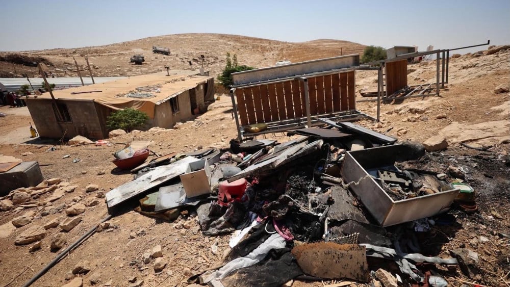 Burned household belongings and twisted metal lie beside rural structures in the village of Tuba in Masafer Yatta, south of Hebron in the occupied West Bank, on August 6, 2026. (AFP)