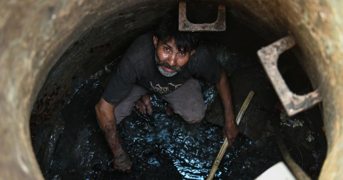 A manual scavenger looks on as he cleans a manhole in the old quarters of New Delhi. | Chandan Khanna/AFP