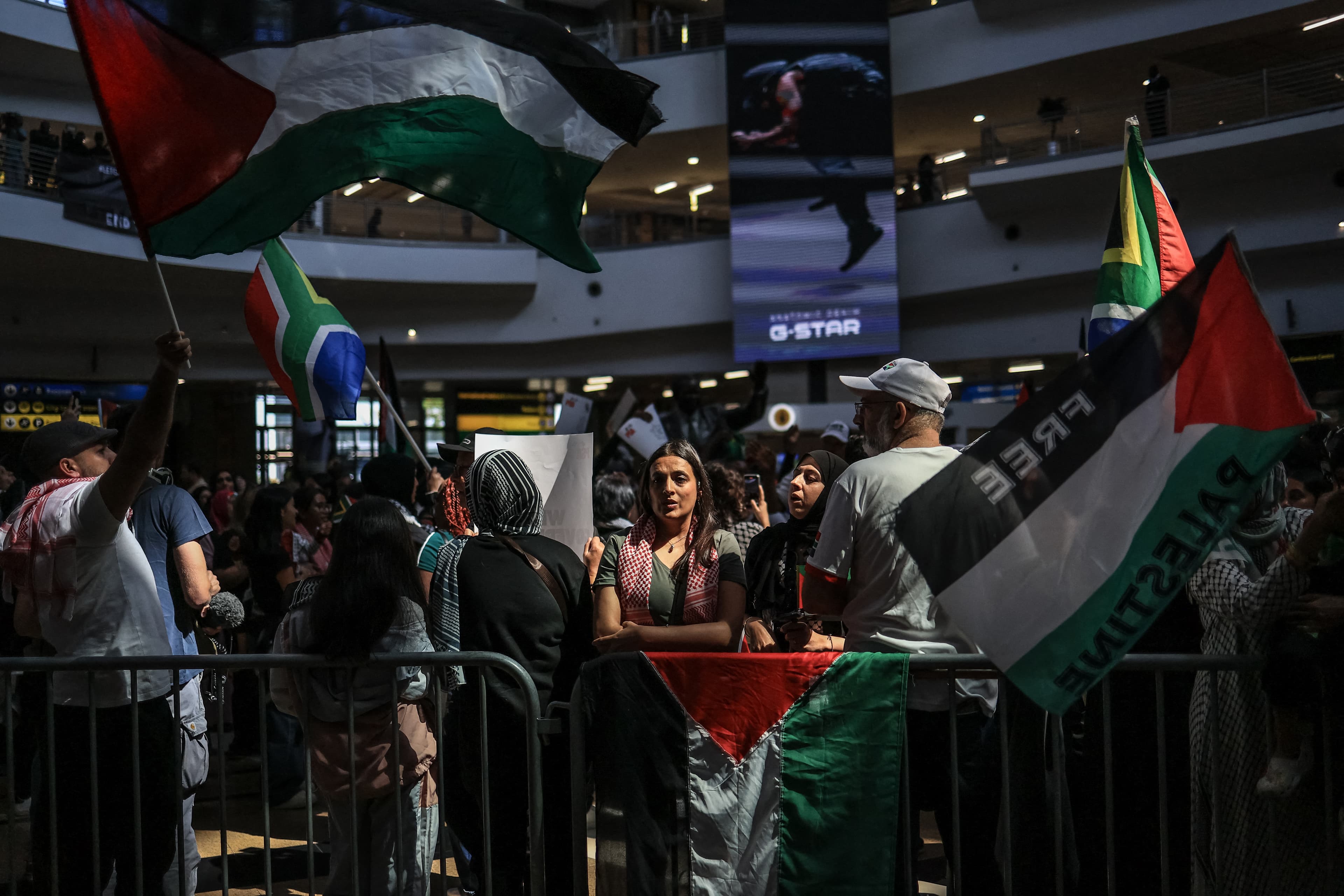 Pro-Palestinian supporters wave flags as they wait for the arrival of South African activists at OR Tambo International Airport in Kempton Park