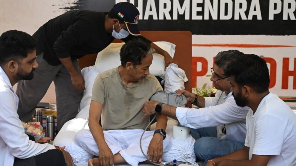 Cockroach Janta Party (CJP) founder Abhijeet Dipke (R) watches as doctors check activist Sonam Wangchuk’s vital signs during his hunger strike in New Delhi on July 15, 2026, demanding the resignation of India’s Education Minister Dharmendra Pradhan over a