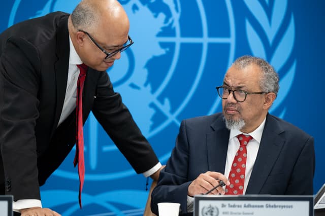 This handhout photograph taken and released on May 7, 2026 by the World Health Organization (WHO) shows its Director-General Tedros Adhanom Ghebreyesus (R) speaking with WHO Health Emergencies Programme executive director Chikwe Ihekweazu prior to a virtu