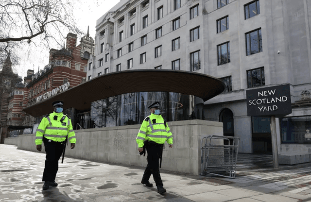 Two Police officers walking outside New Scotland Yard in London.