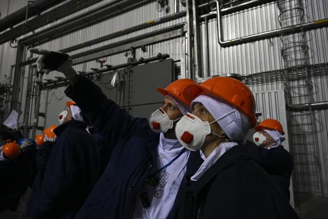 Representatives of Greenpeace and media stand in front of the sarcophagus covering the destroyed fourth reactor under the New Safe Confinement (NSC), at the Chornobyl Nuclear Power Plant on April 9, 2026. (AFP)
