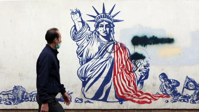 A man walks past a mural depicting the US Statue of Liberty with the torch-bearing arm broken, painted on the outer walls of the former US embassy, in Tehran on February 6, 2026. (Photo: AFP/File)