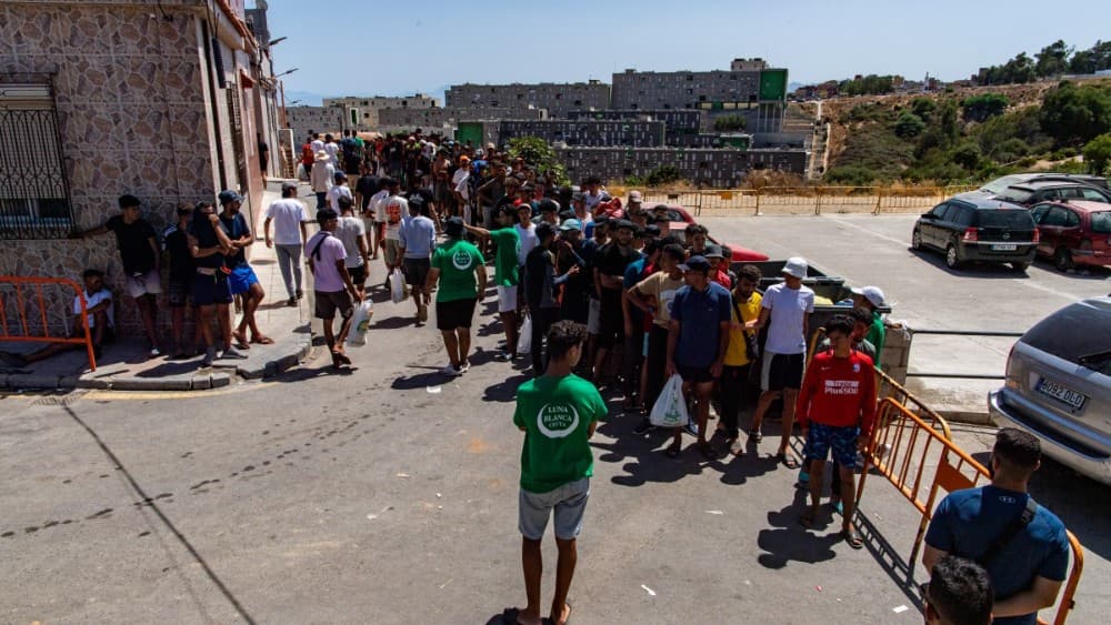 Migrants queue to get food distributed by NGO Luna Blanca in the Spanish North African enclave of Ceuta on August 7, 2026, following a mass influx of migrants from Morocco in recent days. (Photo: AFP)