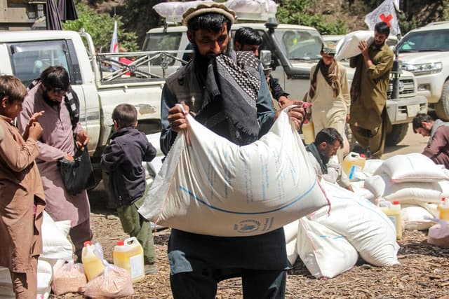 An Afghan man carries food aid distributed by the International Committee of the Red Cross (ICRC) in the Kamdesh district in Nuristan province on April 22, 2026. (AFP)