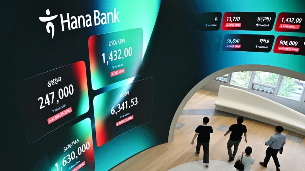 People walk past an electronic screen showing trading figures including South Korea's benchmark stock index (KOSPI) outside a foreign exchange dealing room at the Hana Bank headquarters in Seoul on July 31, 2026. (Photo: AFP)