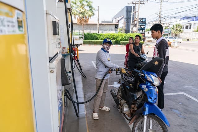 An employee fills the tank of a motorcycle at a gas station in the Donkoi district of Vientiane on March 10, 2026, amid rising petrol prices (AFP)