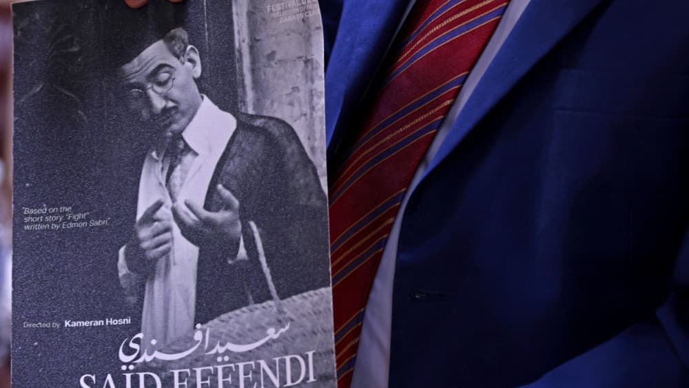 An Iraqi director holds a vintage movie poster from the collection stored at the National Center for Archives and Iraqi Memory in Baghdad on June 14, 2026. (AFP)