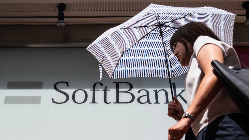 A commuter walks past a Softbank logo on the side of a building in Tokyo on August 6, 2026. (Photo: AFP)