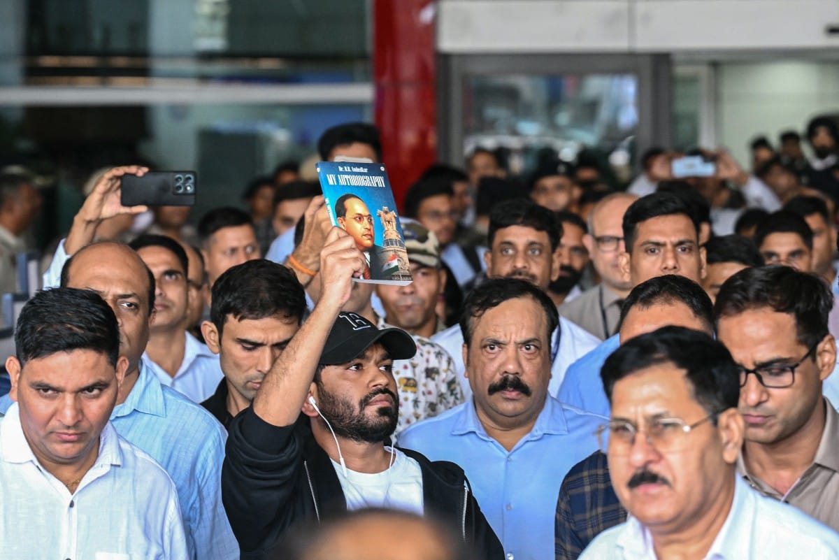 Founder of the Cockroach Janta Party (CJP), Abhijeet Dipke (C) displays the book 'My Autobiography' by the Indian social reformer Dr. B. R. Ambedkar upon his arrival at the airport in New Delhi on June 6, 2026. (AFP)