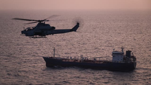 A US Marine Corps AH-1Z Viper attack helicopter patrols near a commercial vessel transiting regional waters as American forces enforce the maritime blockade against Iran. (File photo: US CENTCOM/X)