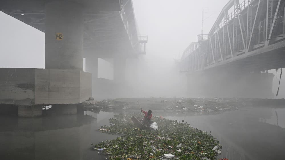 NEW DELHI: A man searches for usable items in the Yamuna River amid dense smog in New Delhi on December 20, 2025. (AFP/File)