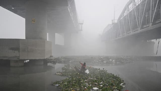 NEW DELHI: A man searches for usable items in the Yamuna River amid dense smog in New Delhi on December 20, 2025. (AFP/File)