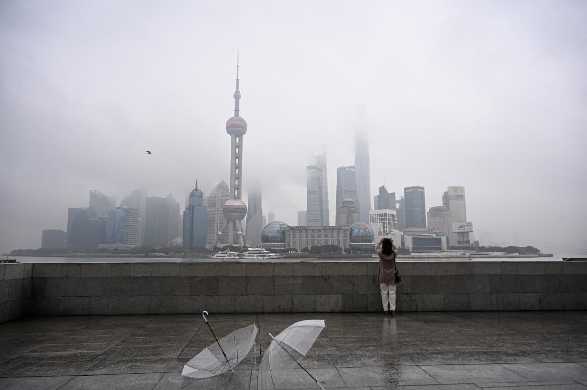 TOPSHOT - A woman takes a photo of the Lujiazui financial district across the Huangpu River on the Bund promenade in Shanghai on March 5, 2026.