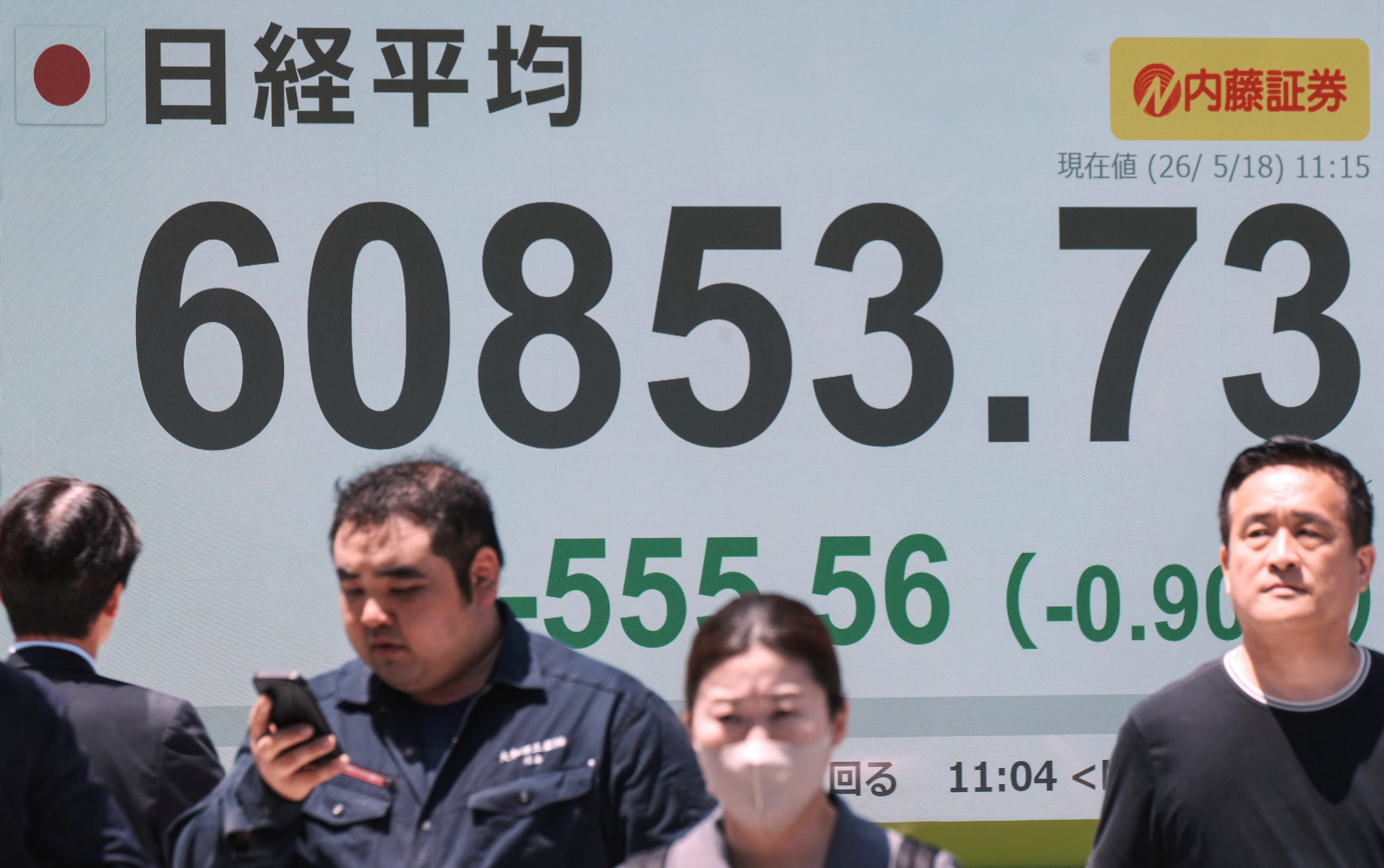 Pedestrians walk past an electronic quotation board displaying the Nikkei Stock Average on the Tokyo Stock Exchange along a street in Tokyo on May 18, 2026. (Photo by Kazuhiro NOGI / AFP) Related content