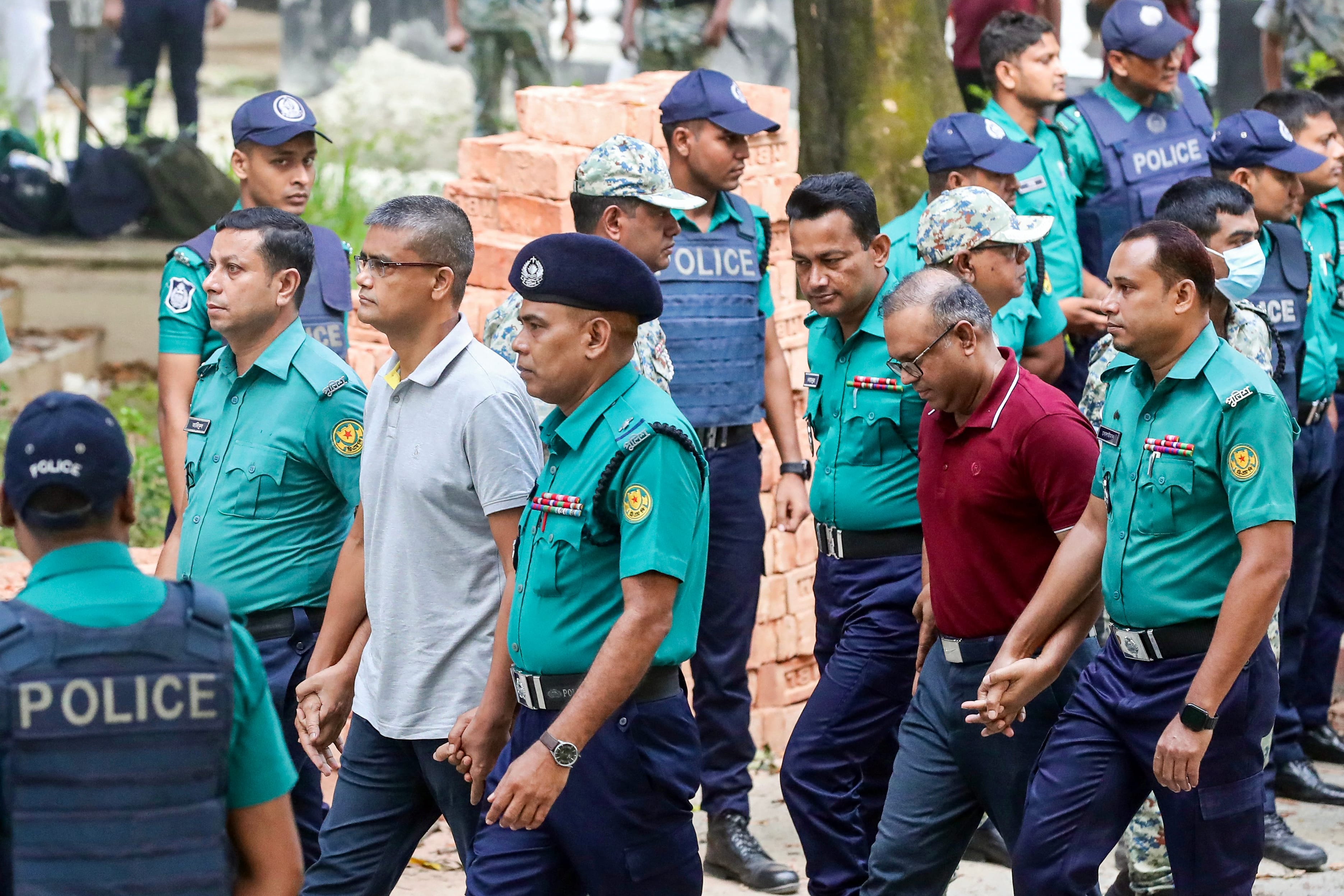 Police personnel escort detained army officers to the International Crimes Tribunal (ICT) court in Dhaka on October 22, 2025, over charges of crimes against humanity. (AFP)