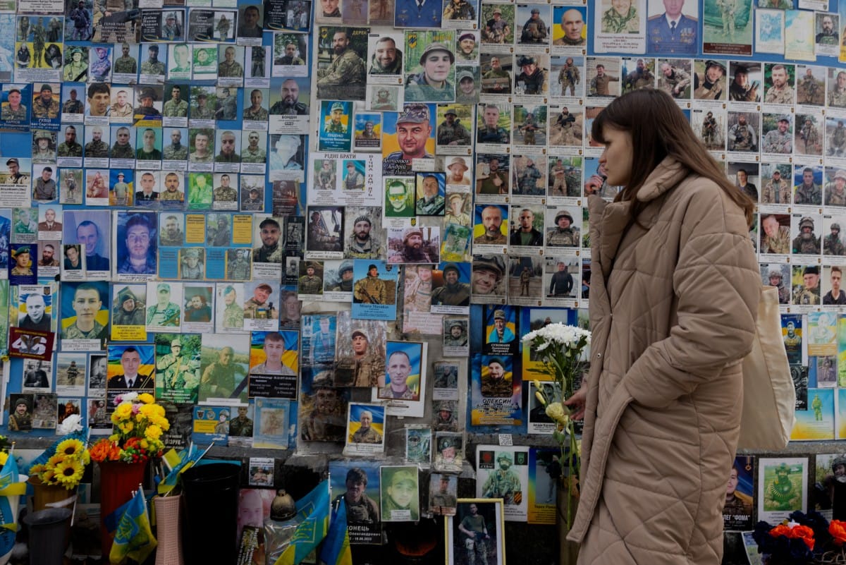 A woman holding flowers pays her respect at the Wall of Remembrance of the Fallen for Ukraine in Kyiv on February 24, 2026, as Ukraine marks the fourth anniversary of Russia's invasion. (AFP)
