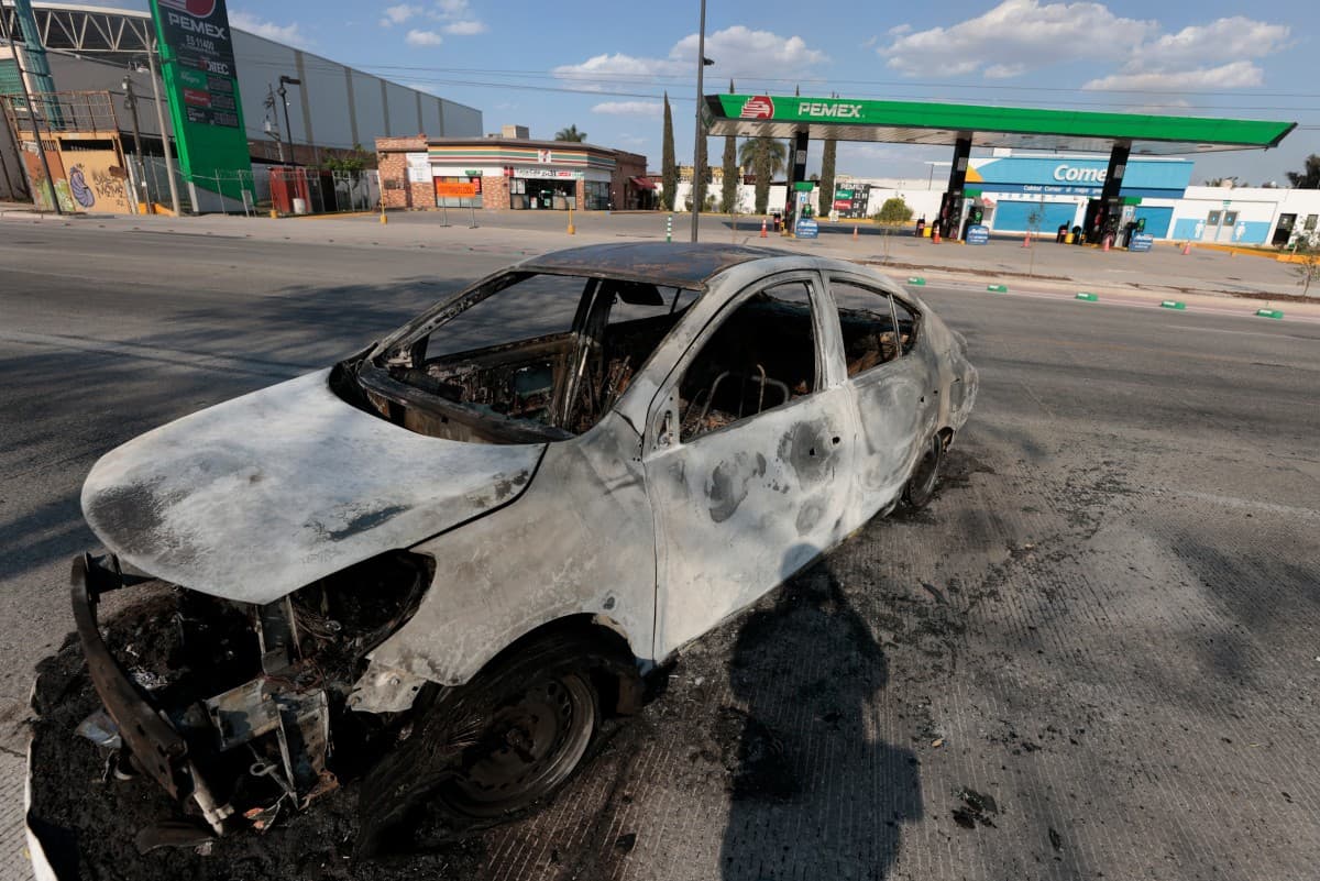 A view of a burned car, allegedly set on fire by crime groups in response to an operation to arrest a high-priority security target, on a highway near Tlajomulco de Zuniga, Jalisco state, Mexico, on February 22, 2026. (AFP)