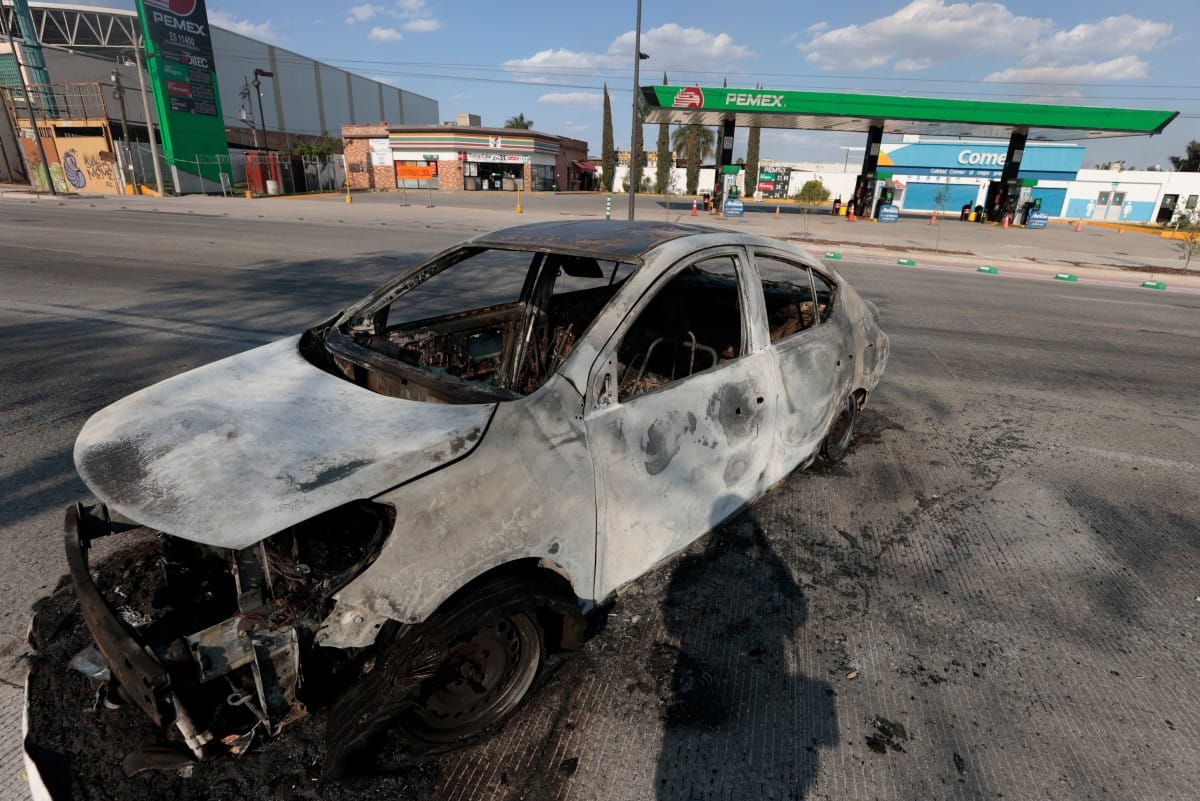 A view of a burned car, allegedly set on fire by crime groups in response to an operation to arrest a high-priority security target, on a highway near Tlajomulco de Zuniga, Jalisco state, Mexico, on February 22, 2026. (AFP)
