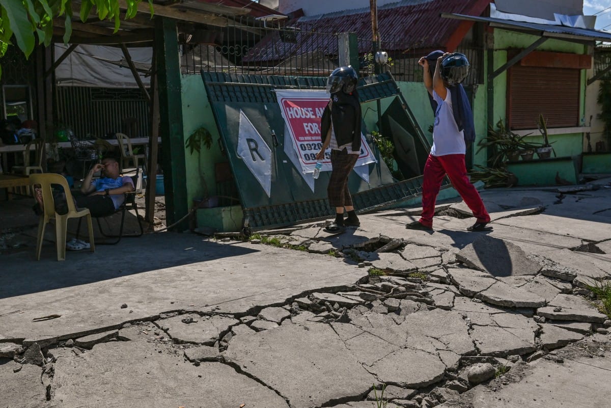 People walk along a damaged road after a 7.8 magnitude earthquake in General Santos City on June 9, 2026 (AFP)