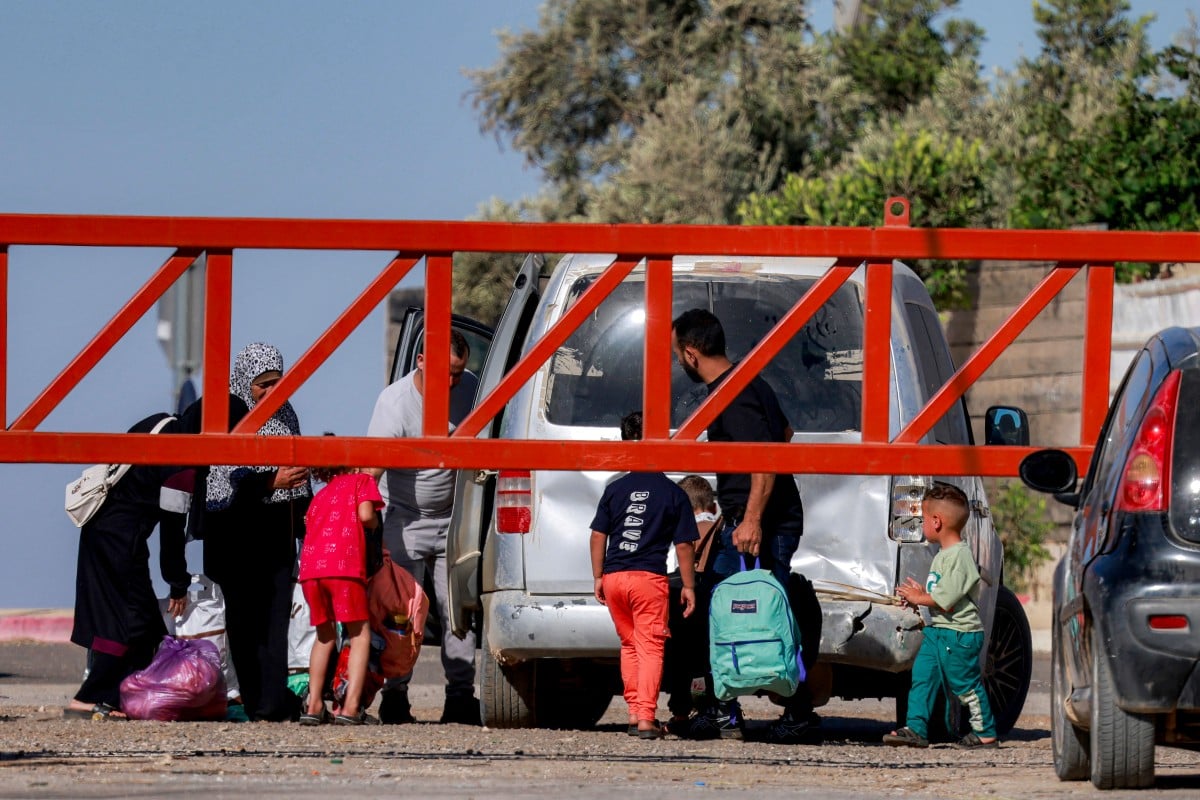 People cross the barrier at the entrance of the Palestinian village of Qusra, south of Nablus in the occupied West Bank, to enter a vehicle on June 30, 2026, as the barrier is closed by Israeli forces. (Photo: AFP)