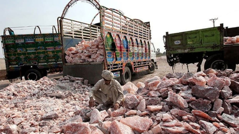 A Pakistani worker collects salt stones to be loaded onto a truck outside the Khewra salt mines.(AFP/File)