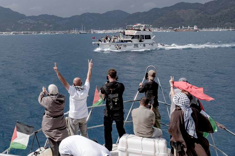 People raise V-signs and take photos from a boat decorated with Palestinian flags as another vessel displaying solidarity signs sails past near the port in Marmaris, Turkey, on May 14, 2026. (AFP)