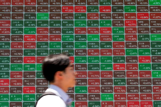 A man walks past an electronic quotation board displaying the Nikkei 225 stock prices on the Tokyo Stock Exchange along a street in Tokyo on May 11, 2026. (AFP)
