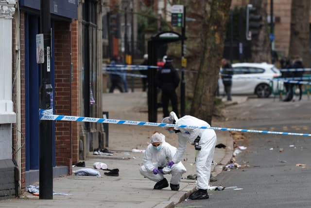 Police forensic officers work amongst a variety of personal items seen covering the road, inside a cordon set up on Friar Gate in central Derby, central England on March 29, 2026, following an incident the night before where a vehicle was driven into pede