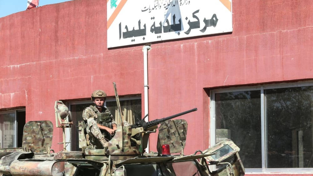 A Lebanese soldier sits on top of a military vehicle outside the municipality building of the southern Lebanese border village of Blida in the aftermath of an Israeli army raid on the village, on October 30, 2025.
