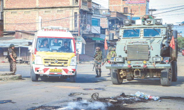 An ambulance rides past a security vehicle positioned in the middle of a road, during a curfew in Imphal on June 9, 2025. Riven by ethnic tensions, Manipur in India's northeast imposed an internet shutdown and curfew after protesters clashed with security