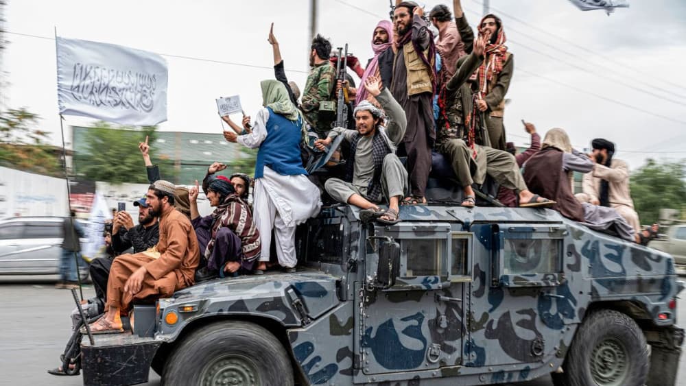 Taliban fighters hold weapons as they ride on a humvee to celebrate their victory day near the US embassy in Kabul on August 15, 2022. (AFP)