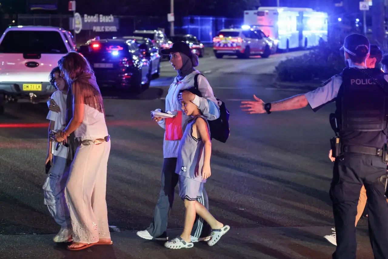 A policeman ushers people across a street after a shooting incident at Bondi Beach in Sydney on December 14, 2025 (AFP)