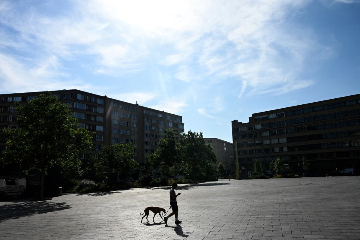 A man walks his dog across the Place Flagey square in Brussels during a heatwave on June 22, 2026.