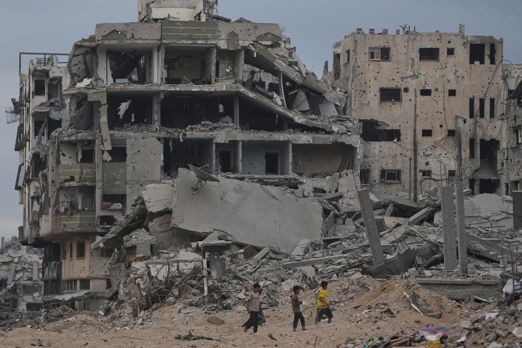 Palestinian children walk past destroyed buildings in the Shati refugee camp in Gaza City, Sunday, Oct. 12, 2025, after Israel and Hamas agreed to a pause in their war and the release of the remaining hostages. (AP)