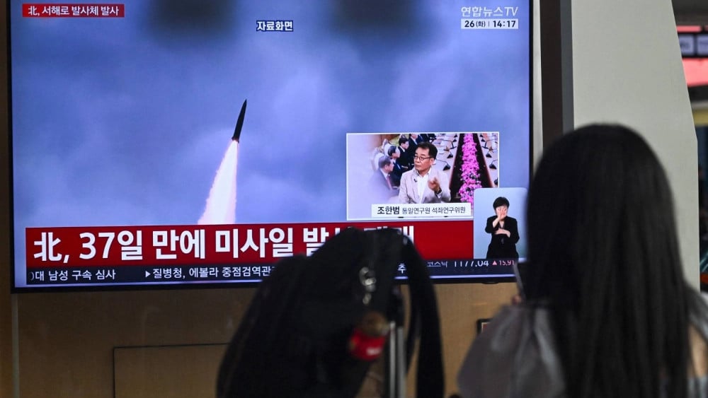 A woman watches a television screen showing a news broadcast with file footage of a North Korean missile test, at a train station in Seoul on May 26, 2026. (AFP)