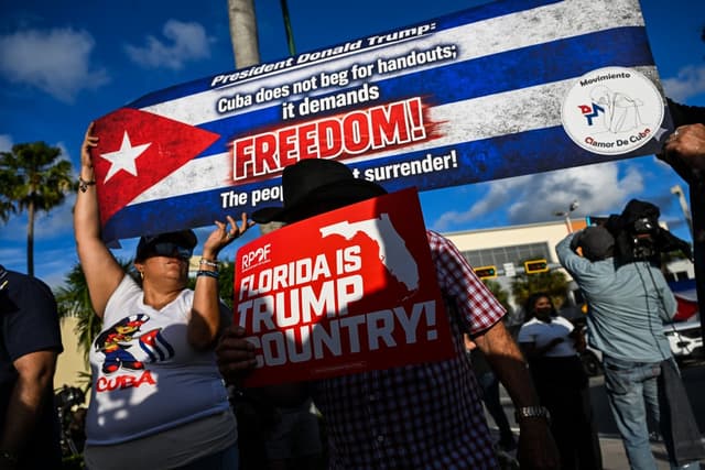 People hold signs outside Versailles Restaurant in support of charges announced by US federal prosecutors against the former Cuban president in Miami, Florida, on May 20, 2026 (AFP)