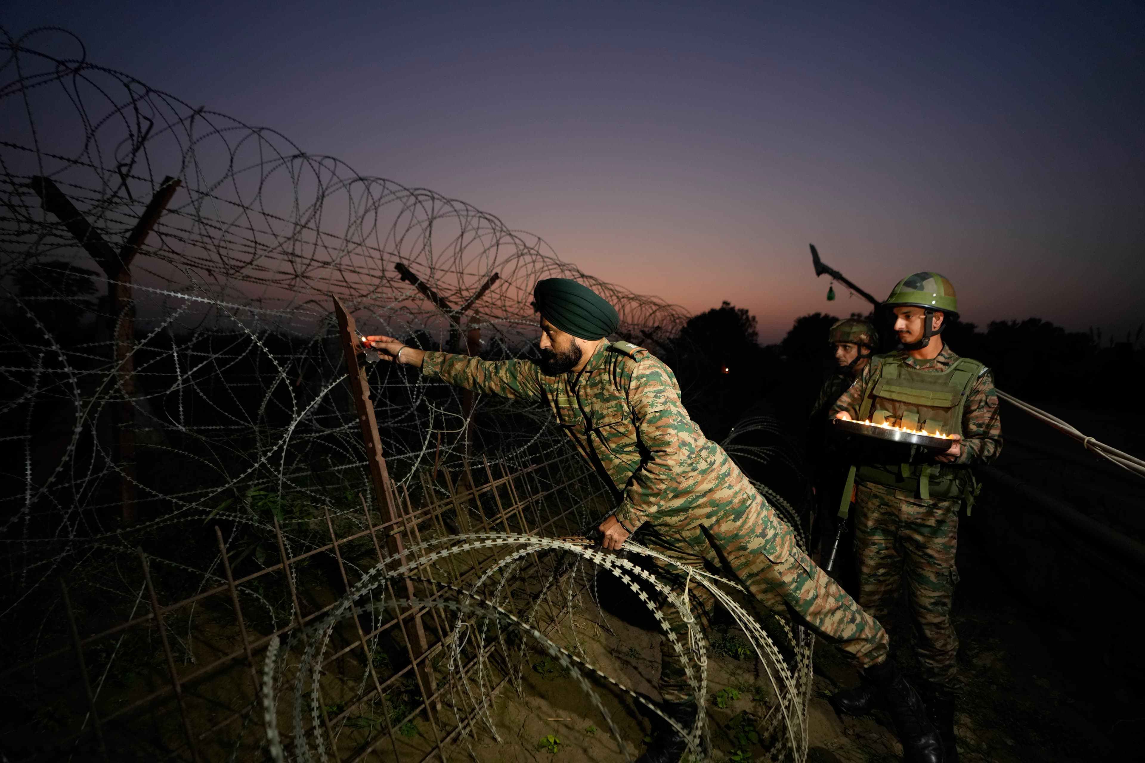 Indian army soldiers light earthen lamp on a fence to celebrate Diwali, near the Line of Control in Akhnoor sector, Indian-occupied Jammu and Kashmir. October 16, 2025. (AP)
