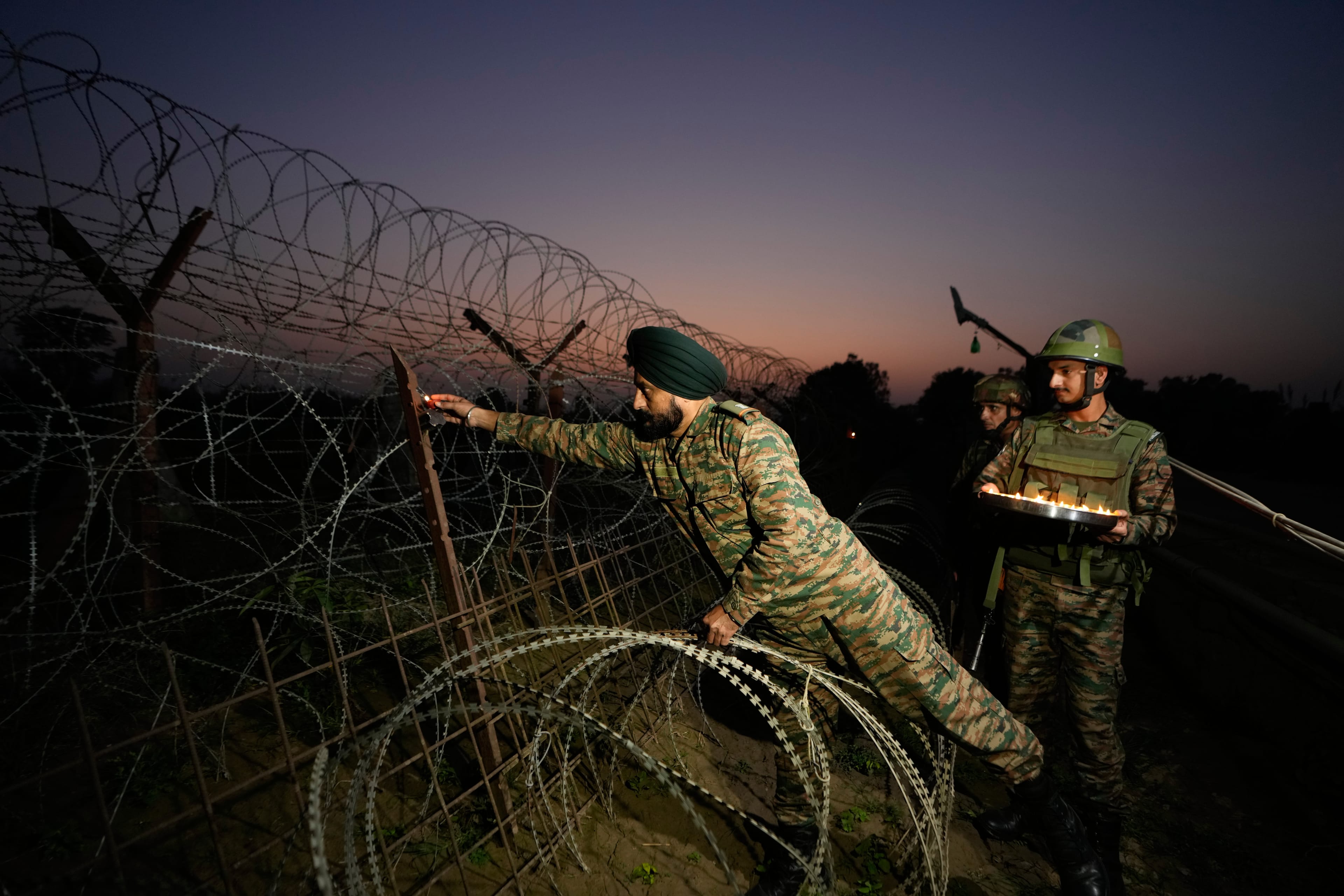 Indian army soldiers light earthen lamp on a fence to celebrate Diwali, near the Line of Control in Akhnoor sector, Indian-occupied Jammu and Kashmir. October 16, 2025. (AP)