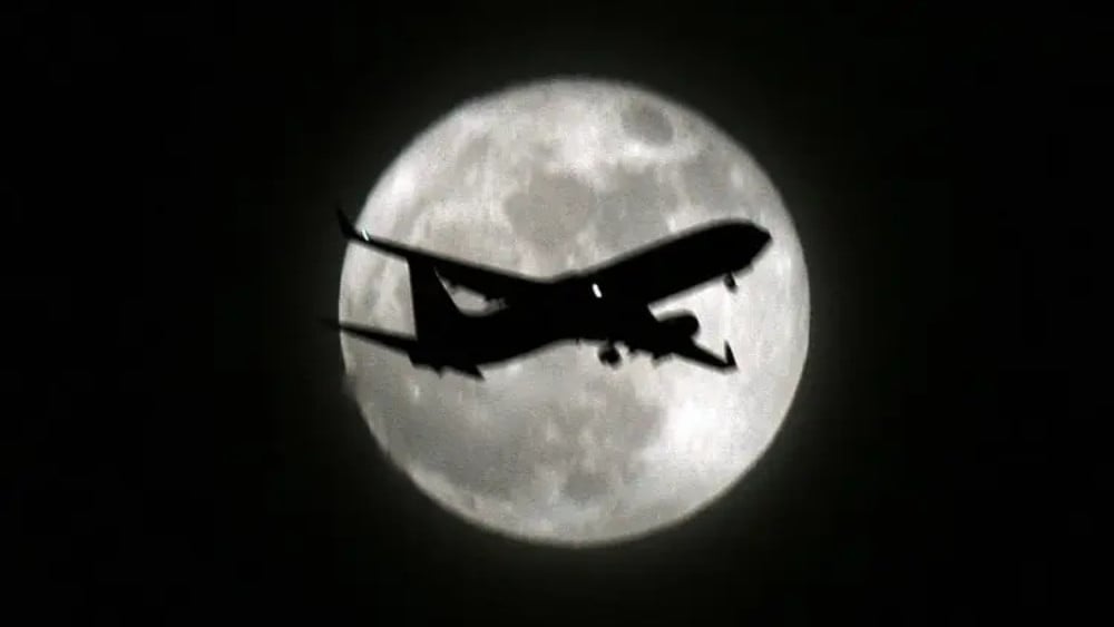 An airplane flies past the full moon over the Indian capital in New Delhi on May 20, 2008. (AFP/File)